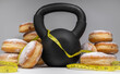 Gym kettlebell, Polish pączki deep-fried doughnuts and tape measure or measuring tape. Fat Thursday (Tłusty czwartek). Pączek, traditional feast day in Poland. Healthy fitness diet choice.