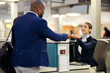 © Nina Lawrenson/peopleimages.com - Businessman, airport and passenger assistant helping traveler with checkin at terminal counter. Black male with passport and service agent in travel help, security or immigration for airline control