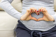 © Andrii - Photo of pregnant woman making heart shape with hands.