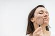 © Andrii - Close up photo of woman with dry skin with magnifying glass.
