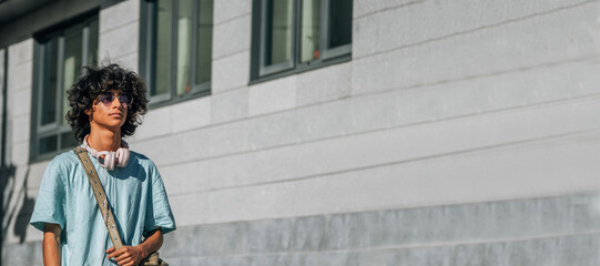 Poster - casual young man with headphones walking around the city