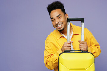 Traveler fun man wear casual clothes hold suitcase look camera isolated on plain pastel light purple background. Tourist travel abroad in free spare time rest getaway. Air flight trip journey concept.