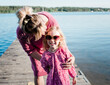 © Cavan Images - mother holding her daughter who is wearing sunglasses smiling