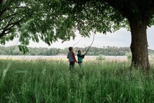 Young Boy And Girl Stood In A Field Playing With Sticks