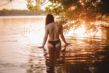 Sensual Woman Standing In Lake Under Tree At Sunset