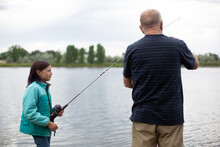 Grandfather Helping Granddaughter With Her Fishing Pole