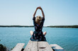 © Cavan Images - woman stretching whilst meditating in front of the sea