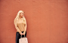 Blonde Female Standing By Orange Wall