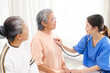 © artitwpd - Asian nurse using a stethoscope for checking the heart rate of the senior female patient at home. Medical assistance . Caregiver nursing home concept.