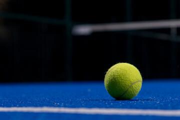 two balls on the surface of a blue paddle tennis court at night