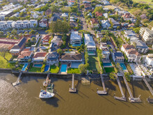 Aerial View Of Waterfront Real Estate With Jetties And Swimming Pools On A River Bank