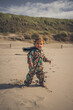 fröhliches Kleinkind am Strand der Ostsee in einem Overall geht barfuß durch den Sand