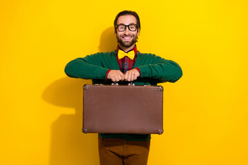 Wall Mural - Photo of young excited satisfied glad smiling brunet hair man wear green cardigan hold suitcase for business trip isolated on yellow color background