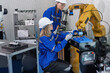 © Tongpool - Female senior robotic engineer in modern factory teach new comer operate and maintenance robot arm