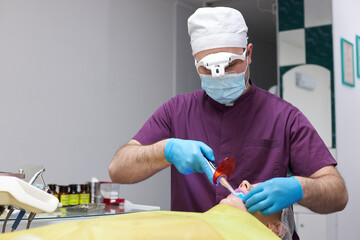 Dental hygienist, dentist doctor using ultraviolet lamp while treating a patient's teeth. Dentistry