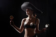 Silhouette of a beautiful young girl in black underwear and a Mexican hat on a dark background. Exotic model posing naked in the studio. Body portrait of sexy girl