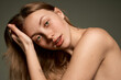 © Lustre Art Group  - Closeup portrait of beautiful young girl with smooth clear skin and without makeup looking at camera with tenderness over grey background. Concept of natural beauty