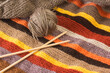 Tejido de lana de colores junto a un ovillo y unas agujas de madera de bambú. Vista superior y de cerca