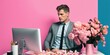 © Uncanny Valley - Handsome man in business suit at his desk in his pink office at laptop with fresh beautiful flower bouquets. Pleasant working environment. Generative AI.