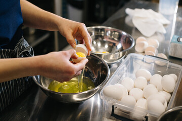 Wall Mural - Close up. A cook in the kitchen of a cafe or bakery. Female hands break eggs for dough.