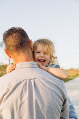 Young man holding his cute 2 years old daughter in light blue outfit