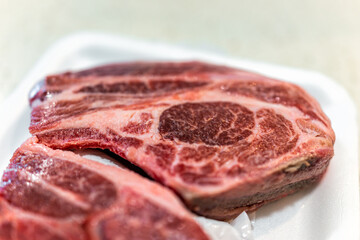 Lamb shoulder blade chops package from butcher on plastic tray with texture closeup of bone and meat and nobody