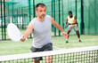 © JackF - Male players playing padel in a padel court outdoor behind the net