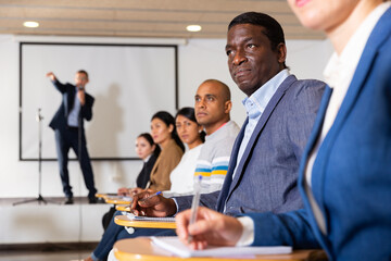 Sticker - Portrait of focused male attentively listening to lecture with colleagues at conference