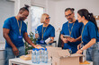 © Zamrznuti tonovi - Diverse volunteers working in a charity donation center and packing clothes and food