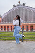 © Oscar - Happy African American woman in casual clothes. She raises her arms in celebration of being at Atocha station in Madrid.