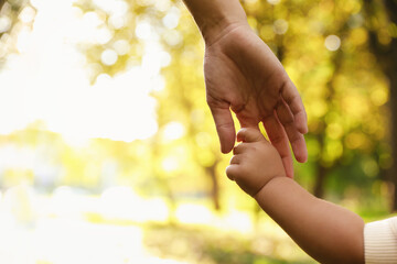 Wall Mural - Daughter holding mother's hand outdoors, closeup. Happy family