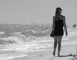 Wall Mural - woman walking on the beach black and white 