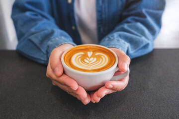 Closeup image of a woman holding coffee cup on the table