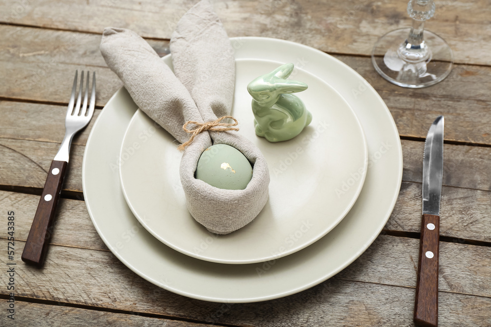 Table setting with Easter egg and bunny on wooden background