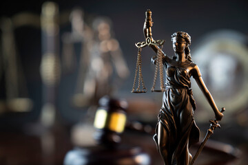 Wall Mural - Law and justice concept. War crimes. Gavel and Themis sculpture in lawyers office. Gray bokeh background.