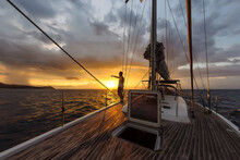 Man On Deck Of Large Yacht Pointing At Sunset On Horizon, Lombok, Indonesia