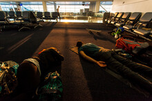 Two Travelers Who Just Took An Overnight Flight Sleeping On The Airport Floor