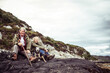 © Cavan Images - retired couple sit with dog on rocks by ocean in rugged scotland