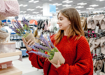 Pretty girl choosing artificial flower for home decoration