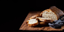 Rustic Sourdough Bread With Cut Slices On A Wooden Table. Panorama, Black Background With Free Space For Text.