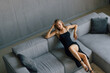 © F8  \ Suport Ukraine - A gorgeous woman in a sexy black evening dress is lying on a black leather sofa.