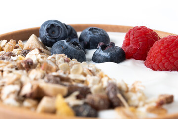 Wall Mural - Yogurt with berries and muesli for breakfast in bowl isolated on white background. Close up