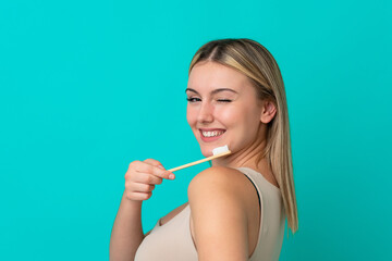 Wall Mural - Young caucasian woman isolated on blue background with a toothbrush and happy expression