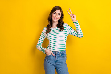 Sticker - Photo of optimistic cheerful good mood smile youngster woman show v-sign put hand denim jeans friendly person isolated on yellow color background