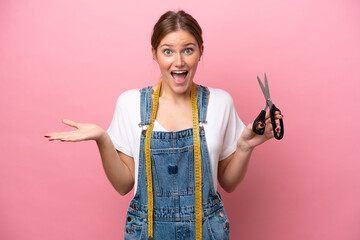 Wall Mural - Young caucasian seamstress woman isolated on pink background with shocked facial expression