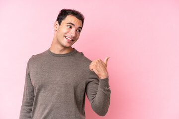 Wall Mural - Young caucasian man isolated on pink background pointing to the side to present a product