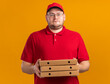 © HN Works - sad overweight young deliveryman in optical glasses holding pizza boxes isolated on orange background with copy space
