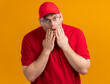 © HN Works - shocked overweight young deliveryman in optical glasses puts hands on face isolated on orange background with copy space
