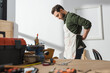 © LIGHTFIELD STUDIOS - Side view of bearded carpenter wearing apron near blurred tools in workshop.