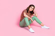 © deagreez - Full body photo of unsatisfied moody lady sit floor arm touch head look empty space isolated on pink color background